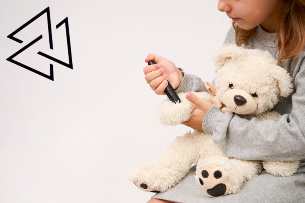 Child demonstrating insulin injection on teddy bear as part of juvenile diabetes education